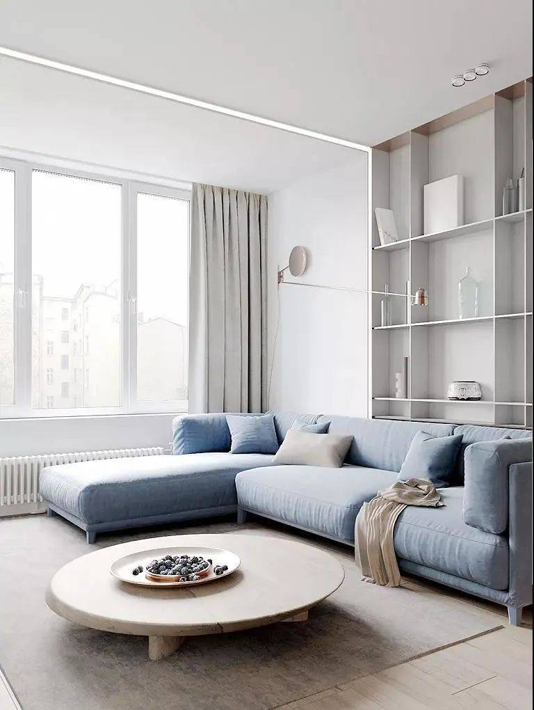 整个空间以白色为基础,木质置物架摆放艺术品增添精致感,蓝色沙发又为