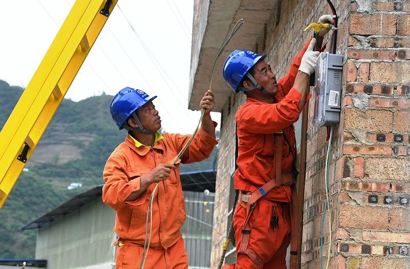 紫云电网建设施工现场,施工人员正在为危改房通电,助村民搬新家.