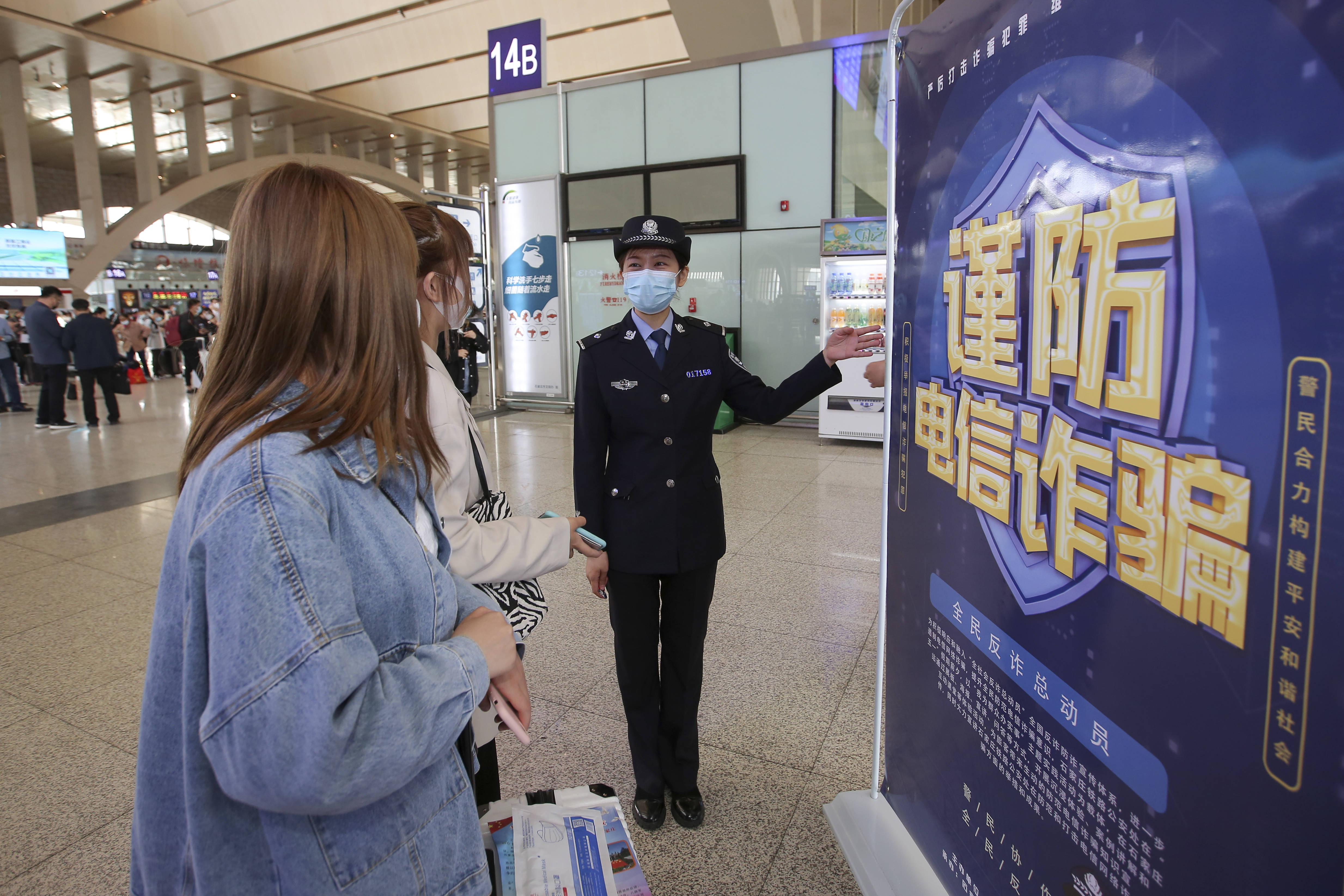 图为民警向旅客介绍此次防范电信网络诈骗宣传活动的具体内容.