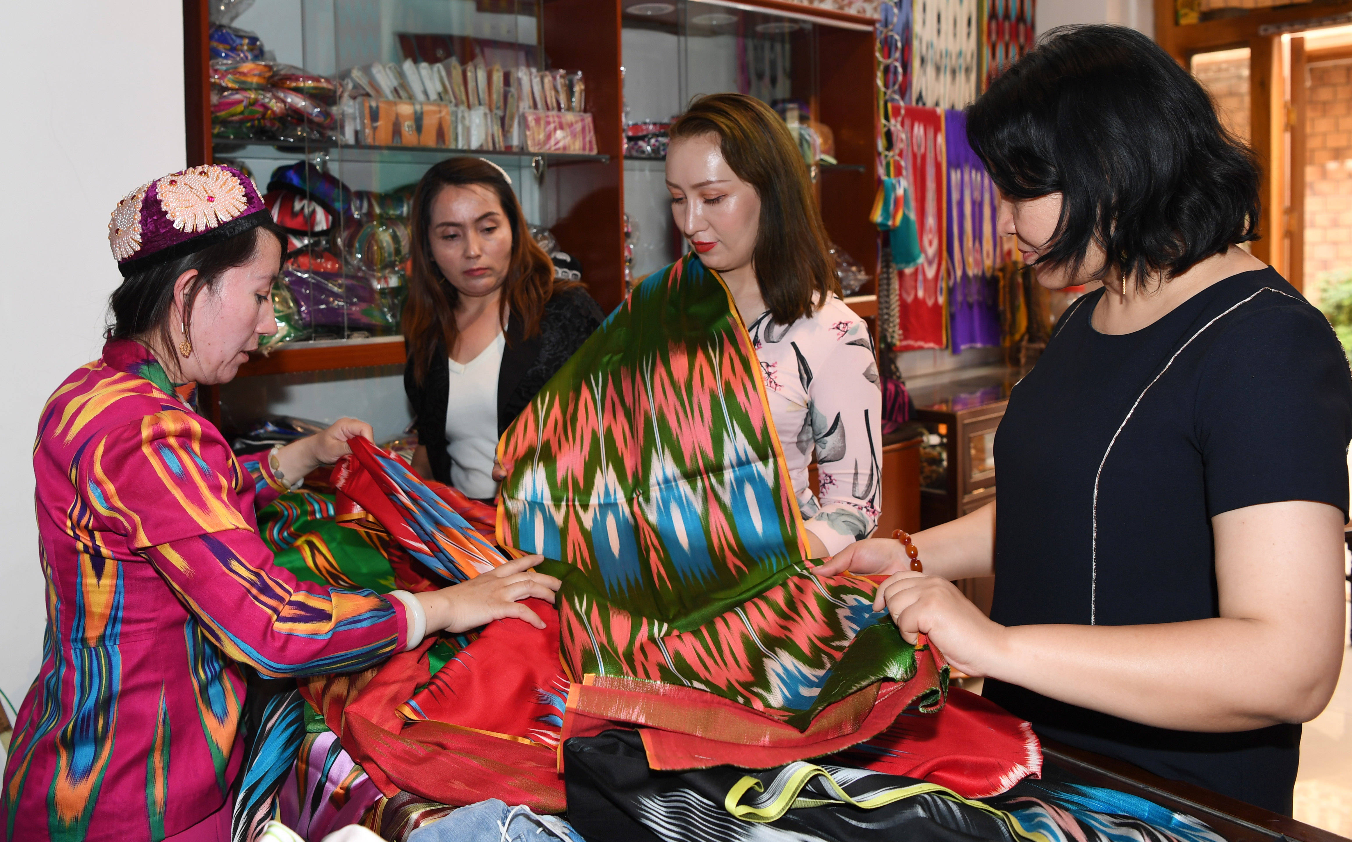顾客在新疆和田市鸽子巷一家艾德莱斯绸店挑选商品(5月26日摄.