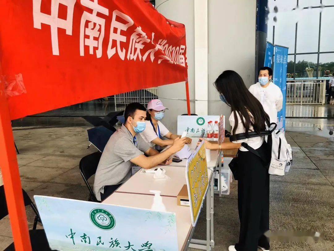 多名老师在出站口手举带有"中南民族大学"字样牌子集中接站,就像迎接