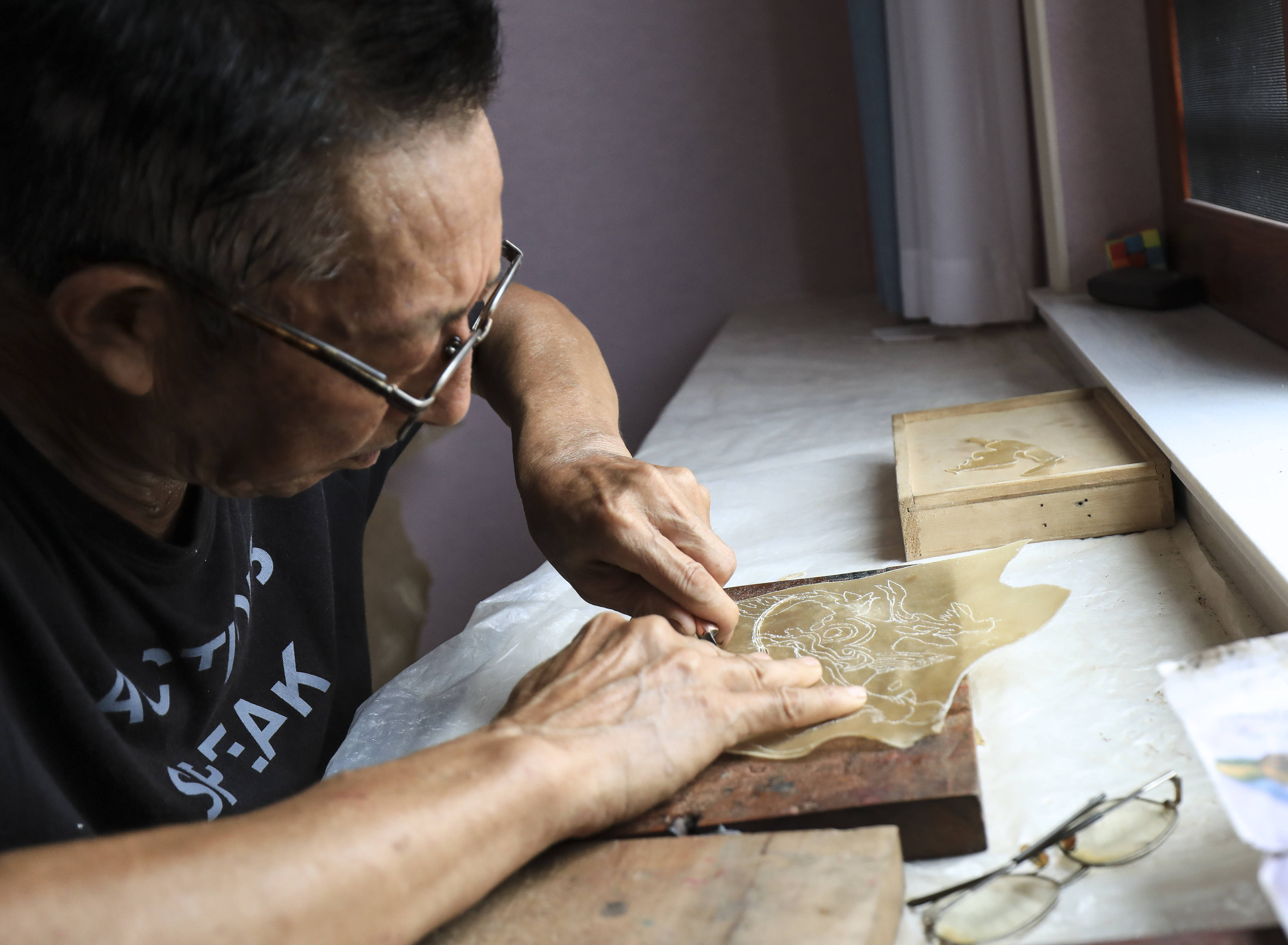 8月1日,皮影艺人蔡善存在家中雕刻制作皮影.