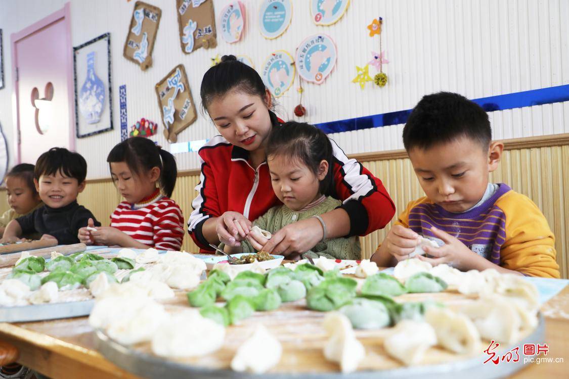 河北省唐山市丰润区阳光金童幼儿园小朋友在老师的指导下学习包饺子