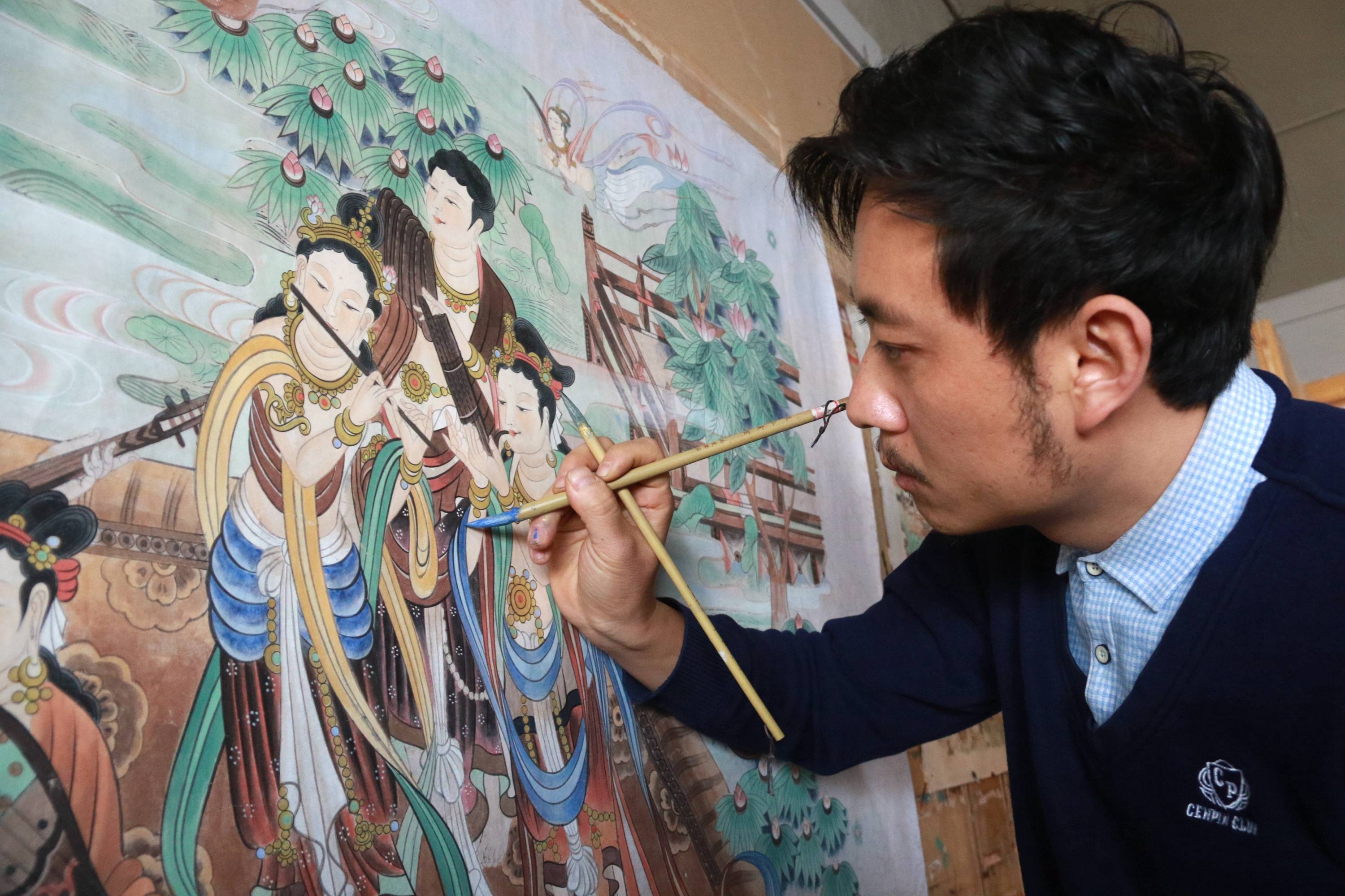 12月10日,在敦煌小镇鸣沙书院,艺术工作者张杰龙在临摹敦煌壁画.