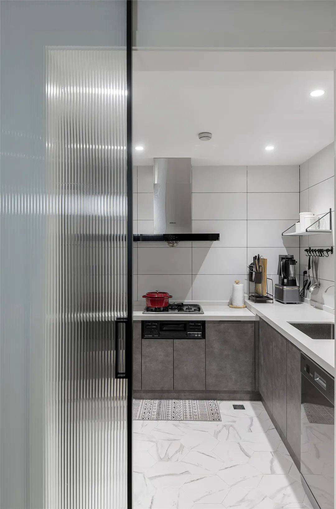 长虹玻璃的厨房门后,白色地砖,墙面砖 灰色橱柜,一种极简的时尚感