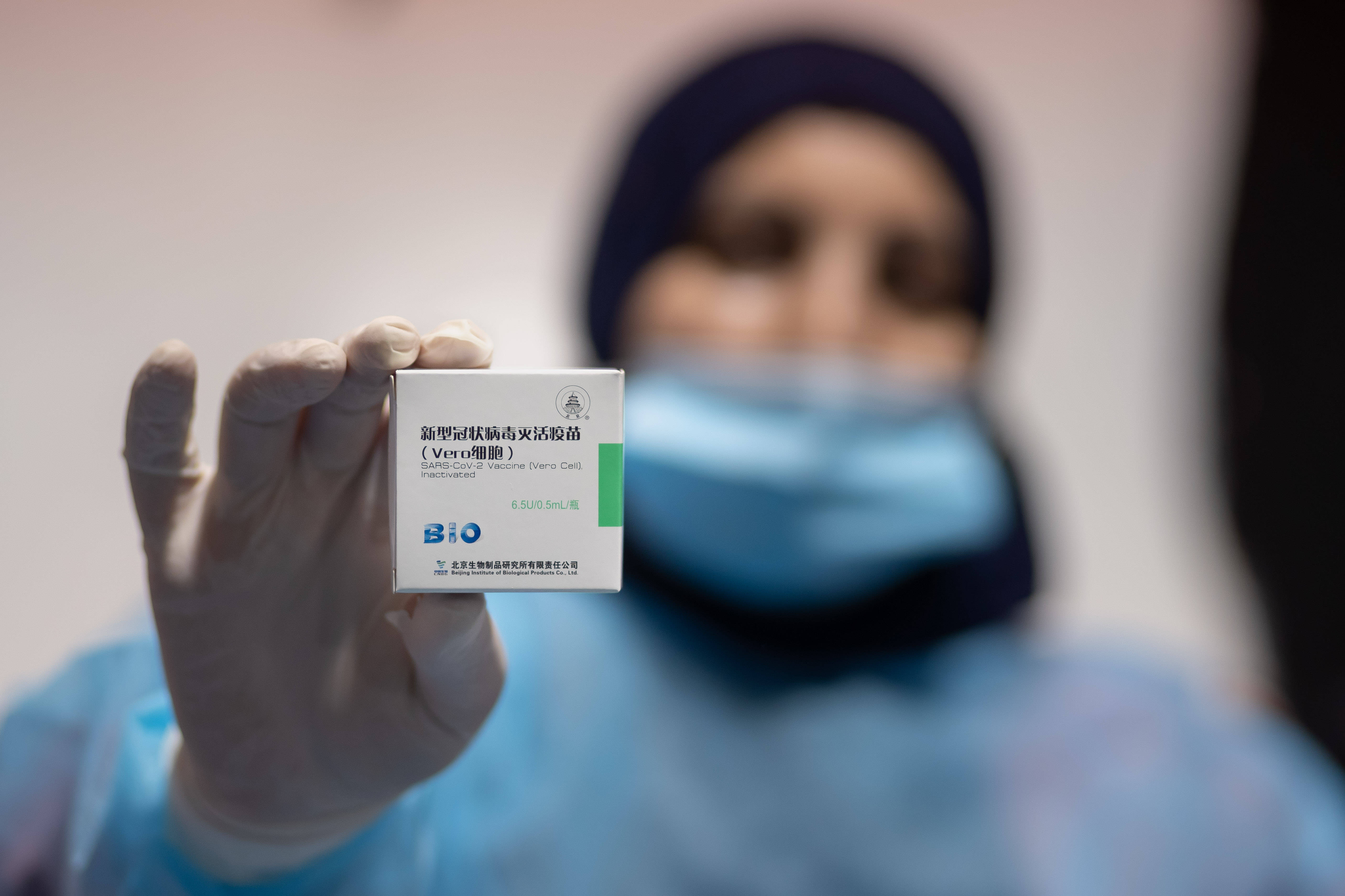医护人员在约旦河西岸城市伯利恒展示中国国药集团新冠疫苗的包装盒