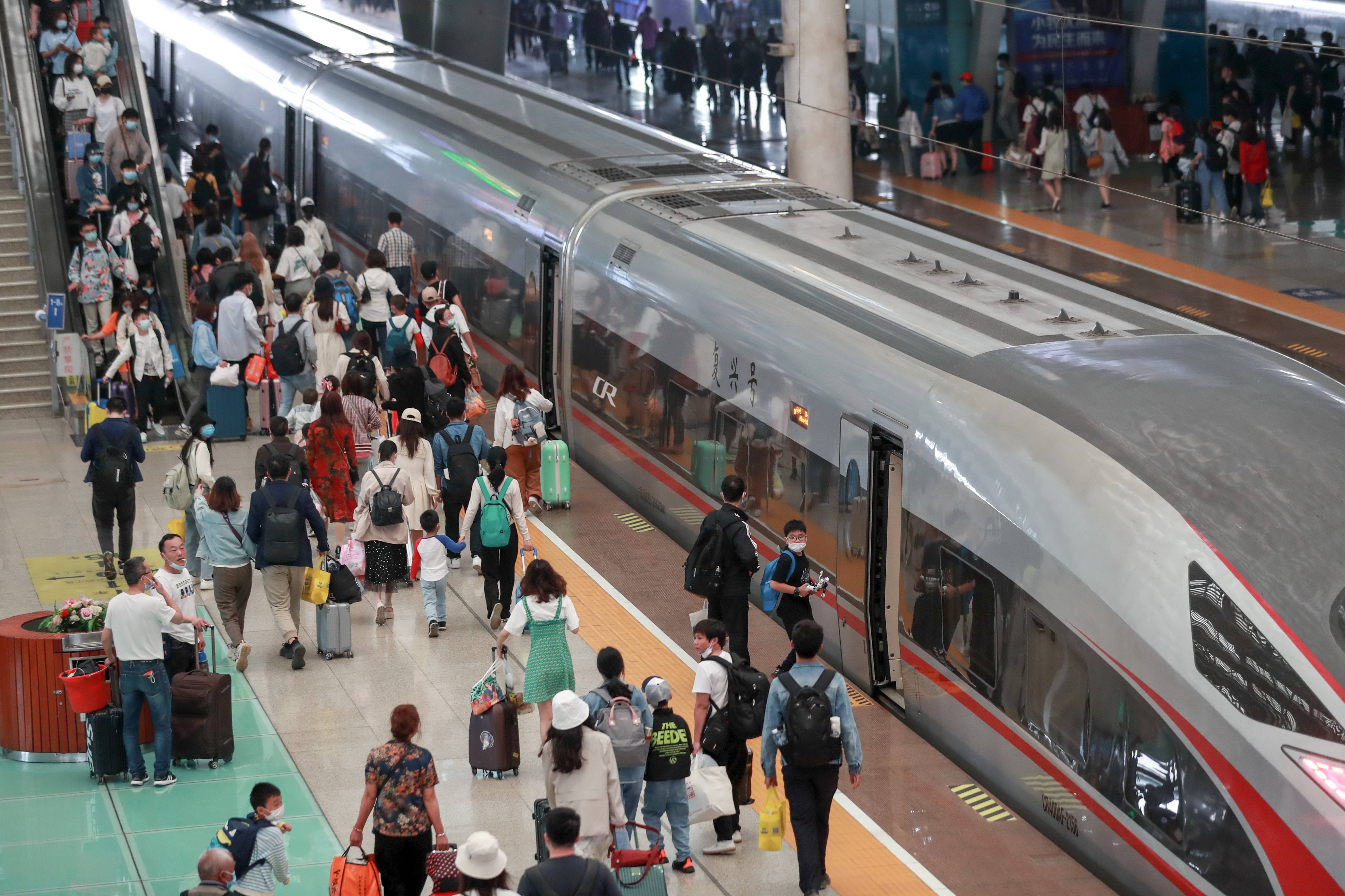 旅客在武汉火车站乘坐高铁列车(5月5日摄).