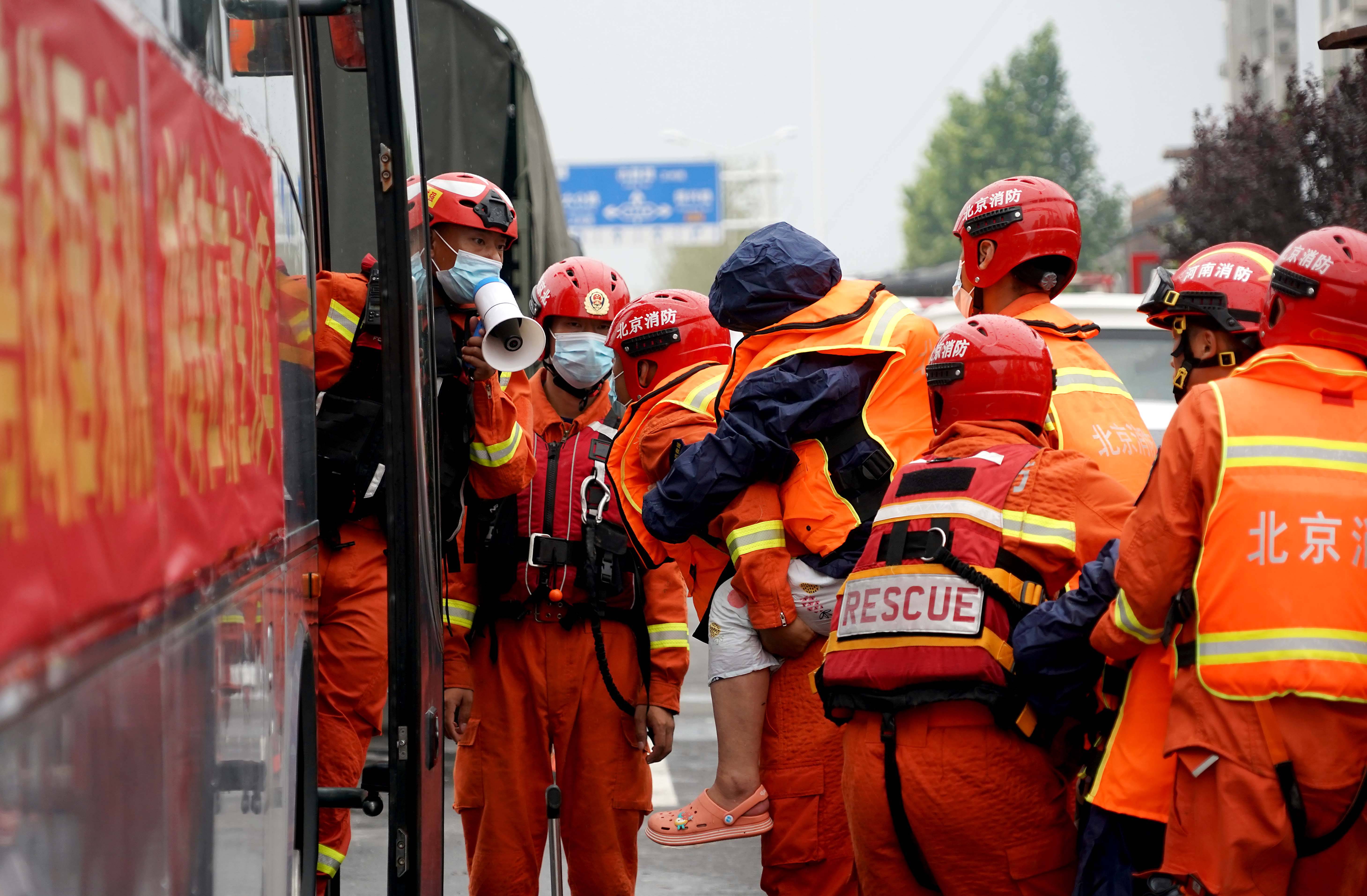 7月28日,在河南省卫辉市,消防救援人员将被困群众转移上大巴车.