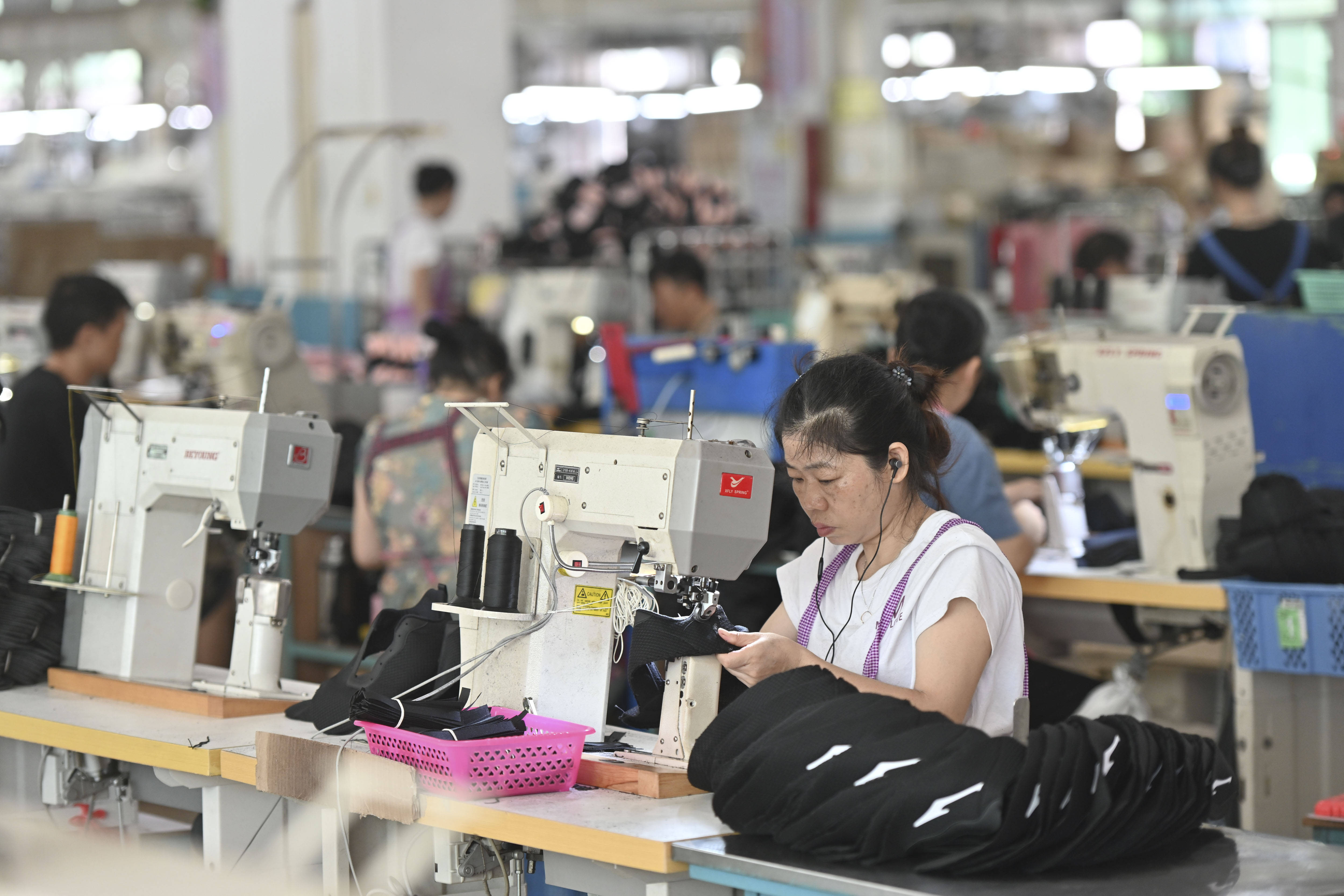 工人在制鞋生产线上操作缝纫机(7月30日摄)