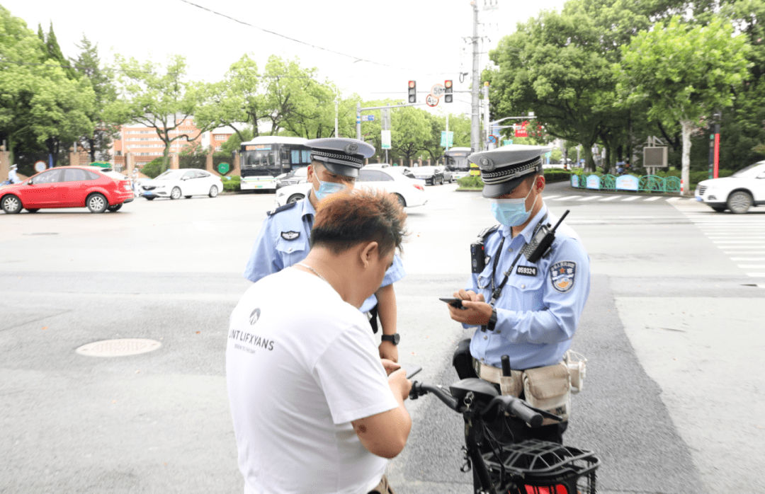 执法人员对骑电动自行车未佩戴头盔的市民进行处罚