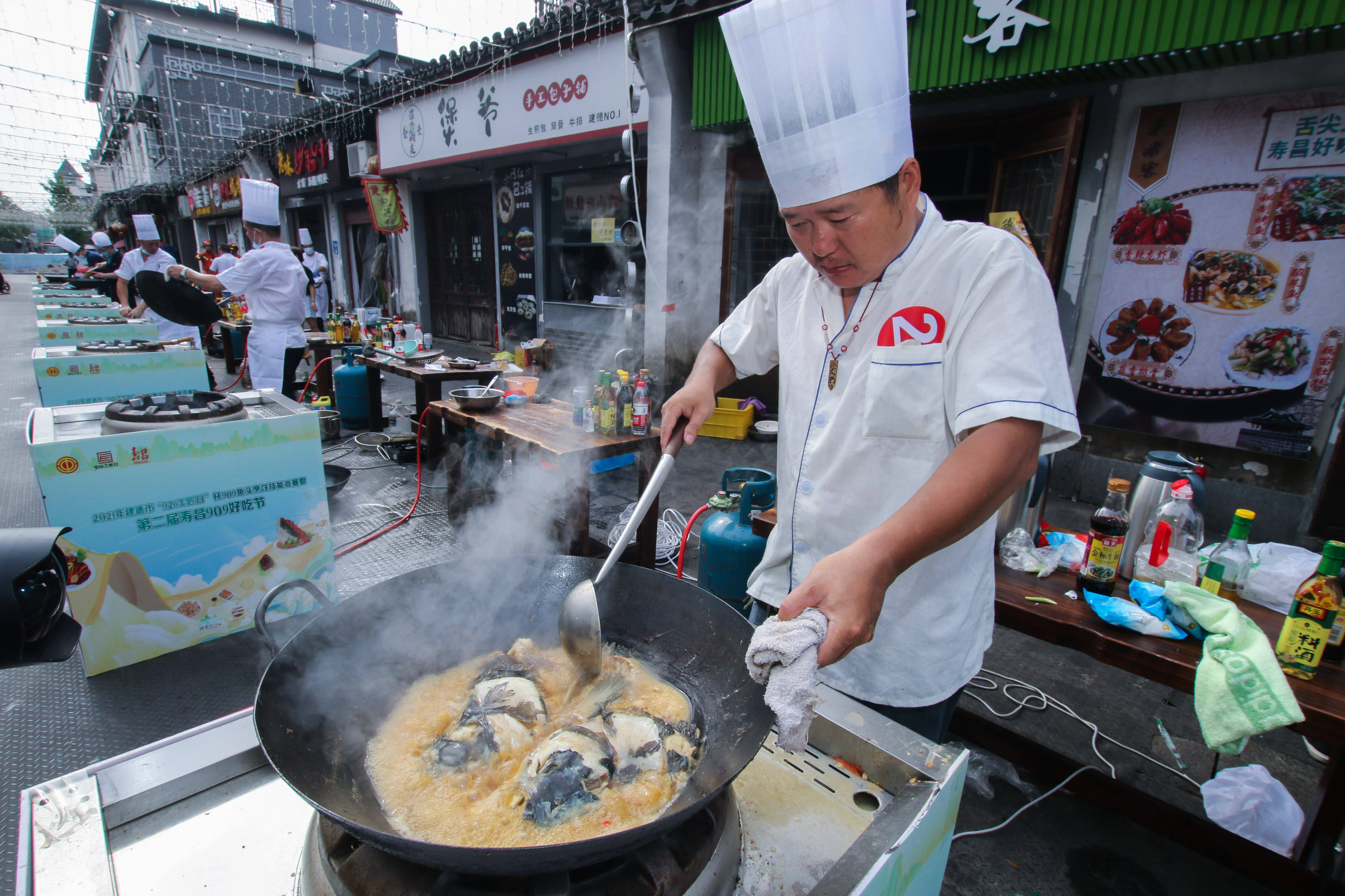 9月9日,厨师在建德市寿昌古镇步行街现场烹饪特色鱼头.