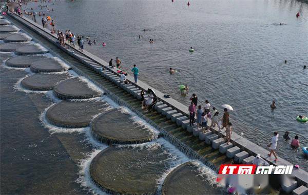 月2日,湖南省永州市道县梅花镇贵头村,游客在叠水汀步桥边上戏水游玩