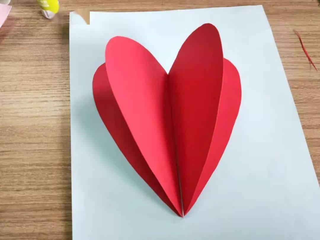 依照下图将爱心拼成草莓的形状;制作步骤:将红色卡纸对折后,画出半个