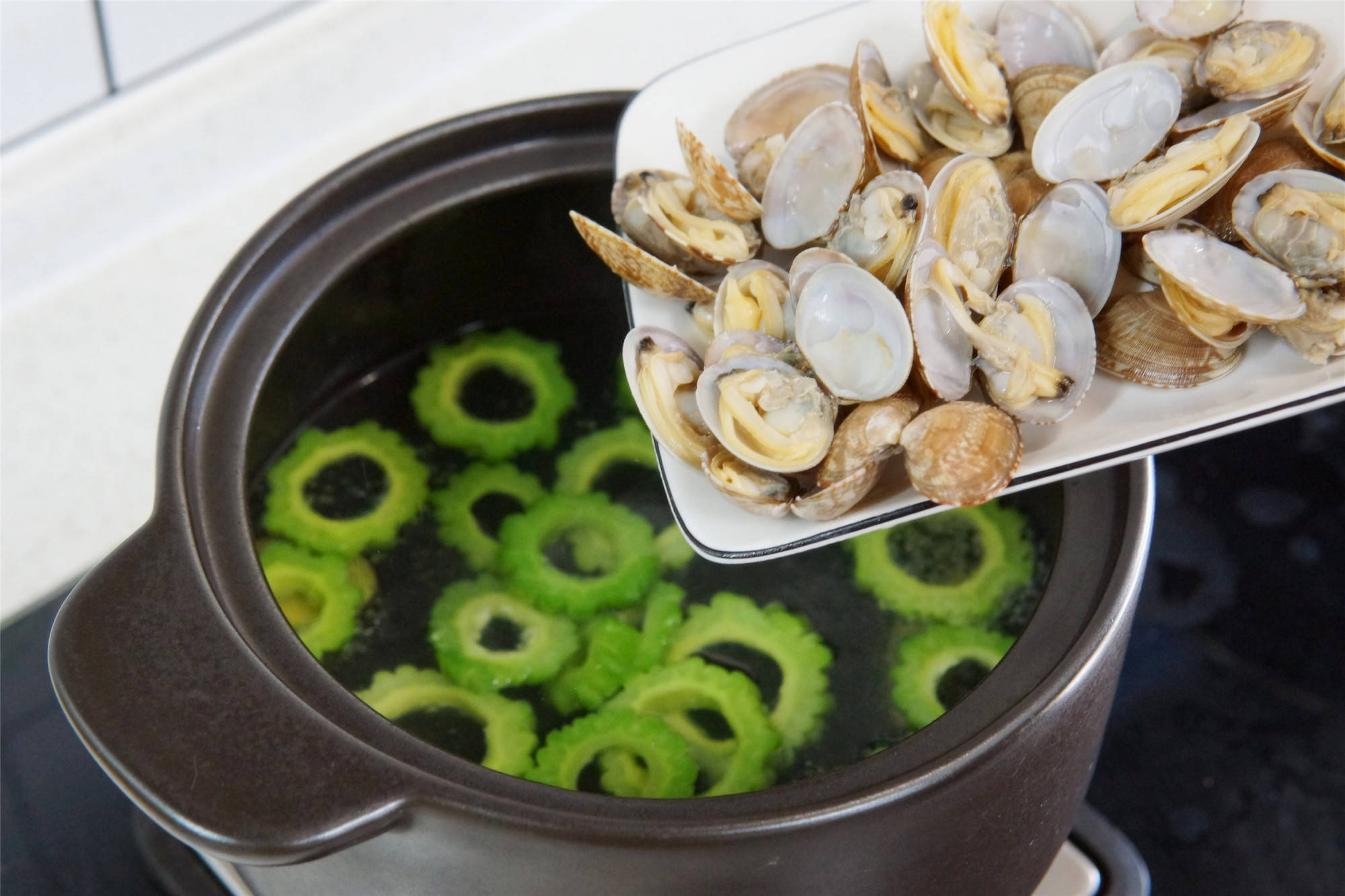 第五步:花甲煮1分钟后关火,加入适量的鸡精和盐,鲜掉眉毛的苦瓜花甲清