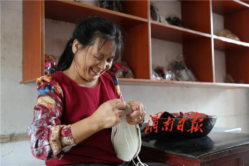 图为7月22日,贫困户王亚锐在家里做布鞋.