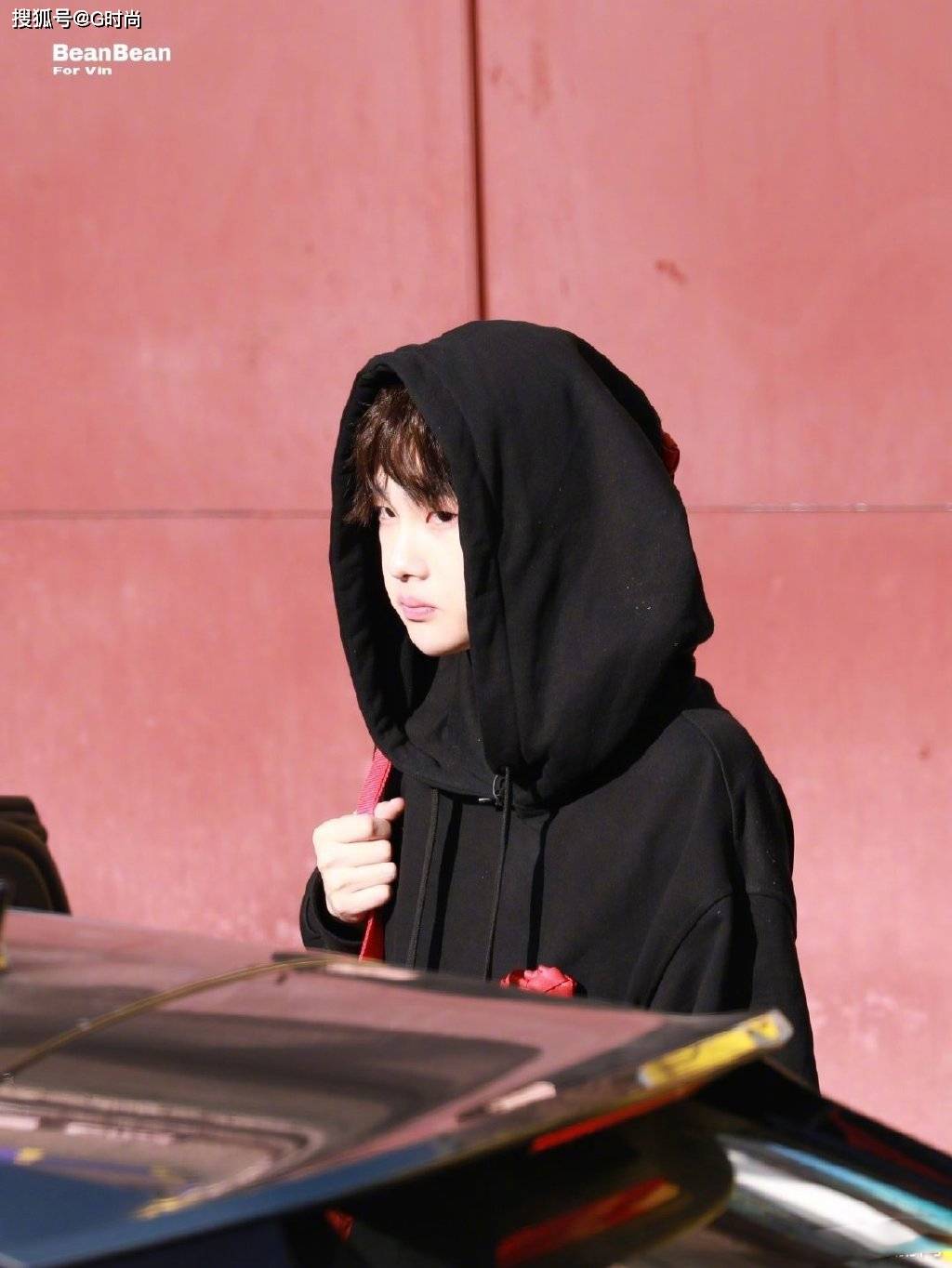 周震南身穿黑色卫衣搭配红色挎包嘟嘴卖萌