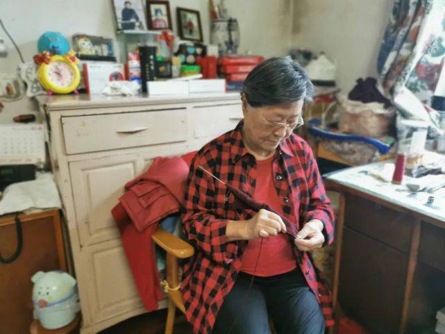 她正坐在椅子上织毛衣,戴着一副老花眼镜,手中的棒针上下翻飞,动作