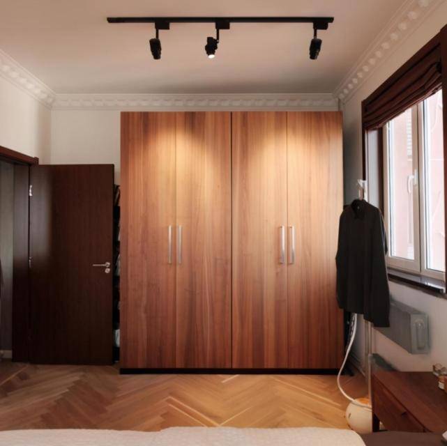床右侧是一组胡桃木色的定制衣柜,打上射灯颜值特别高,储物空间也很大