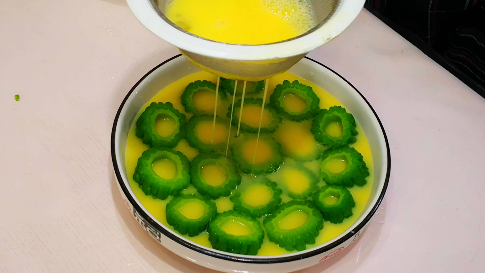 再将鸡蛋打散过滤到装有苦瓜段的盘中,放入锅中蒸熟,出锅后撒点葱花