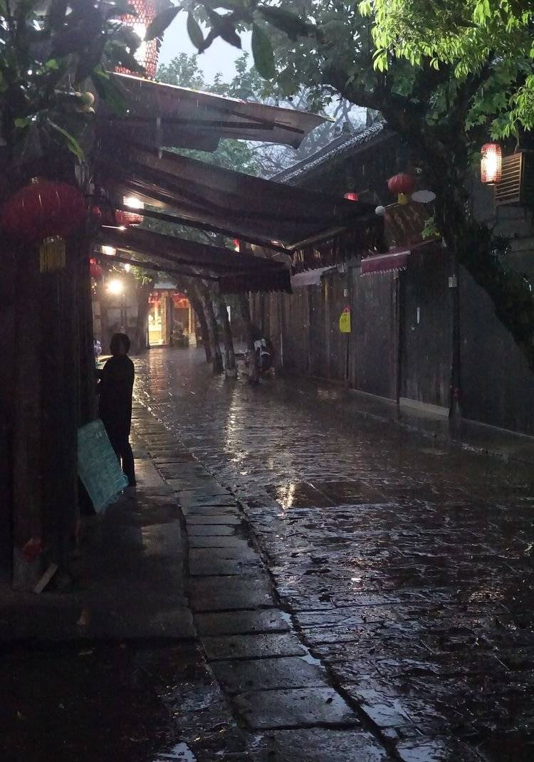 雨夜,打着雨伞慢慢行走在古老的街道上,行人不多,但多数商铺还没有上