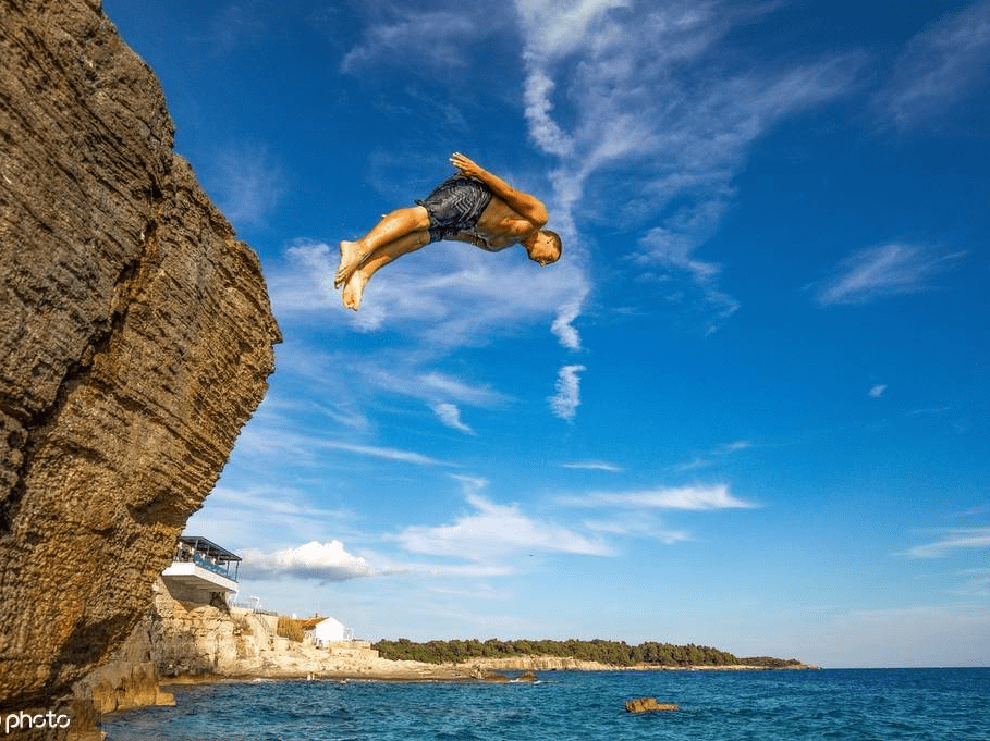 克罗地亚碧海蓝天 年轻人从岩石跳下坠入大海