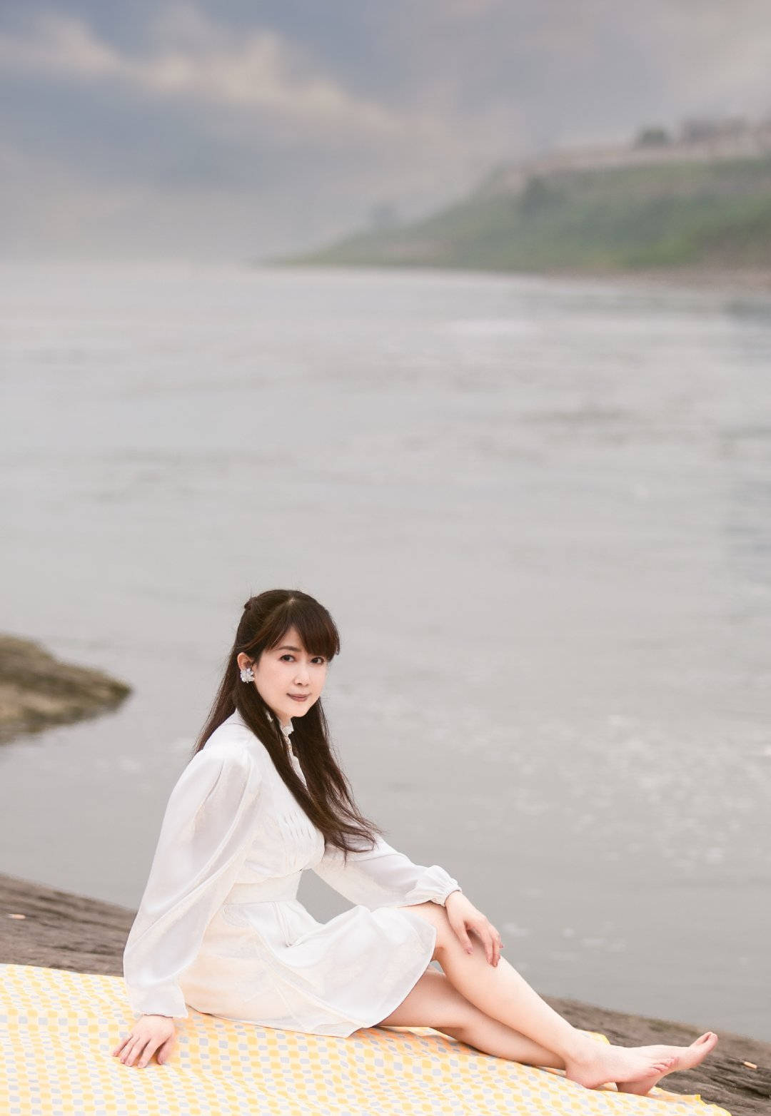 融化在夏天的风中~照片中孟庭苇身穿一身白色连衣裙,长发披肩,站在河