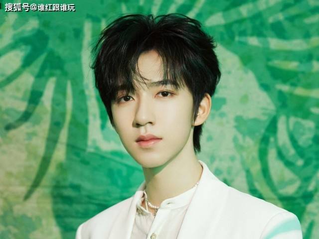 贺峻霖，男，青少年，金色短发，正面微笑，蓝色西装，明亮自然光，舞台背景