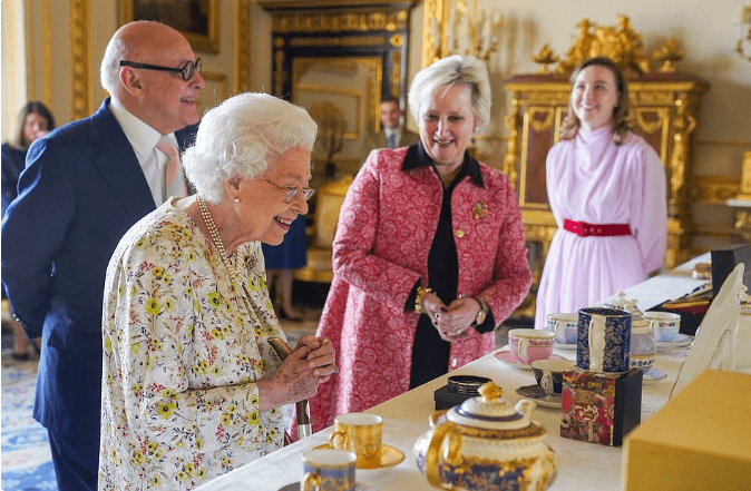 女王 伊丽莎白参观工艺品，穿印花裙涂大红唇，95岁状态和孙媳妇一样美