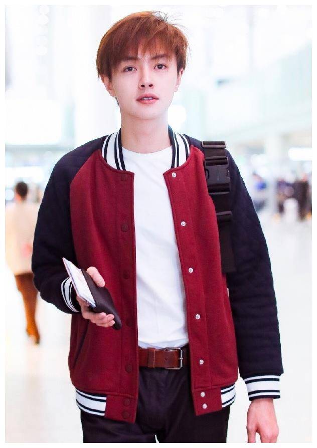 官鸿穿着紫色的衣服. 上半身是紫色的横纹t恤,上面印着涂鸦.