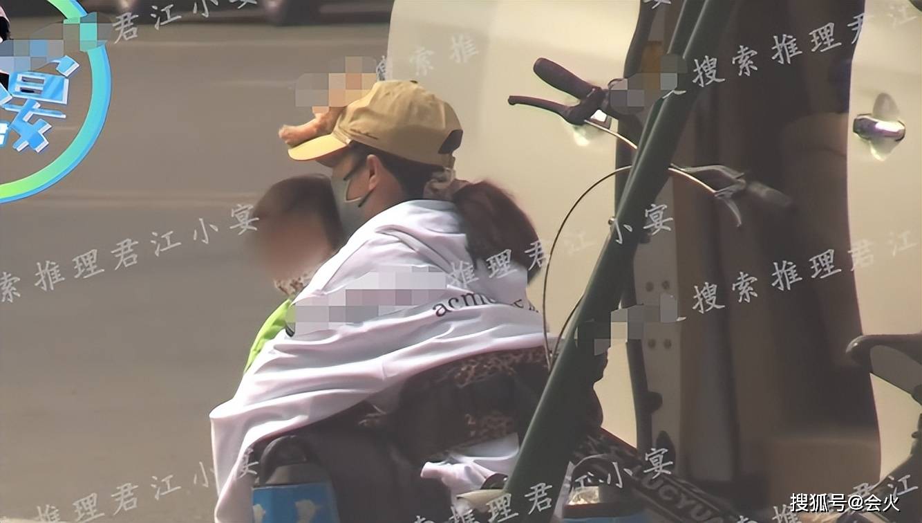 只见谭维维抱着儿子蹲在路边等待老公,她亲昵地抱着孩子,母子俩都戴着