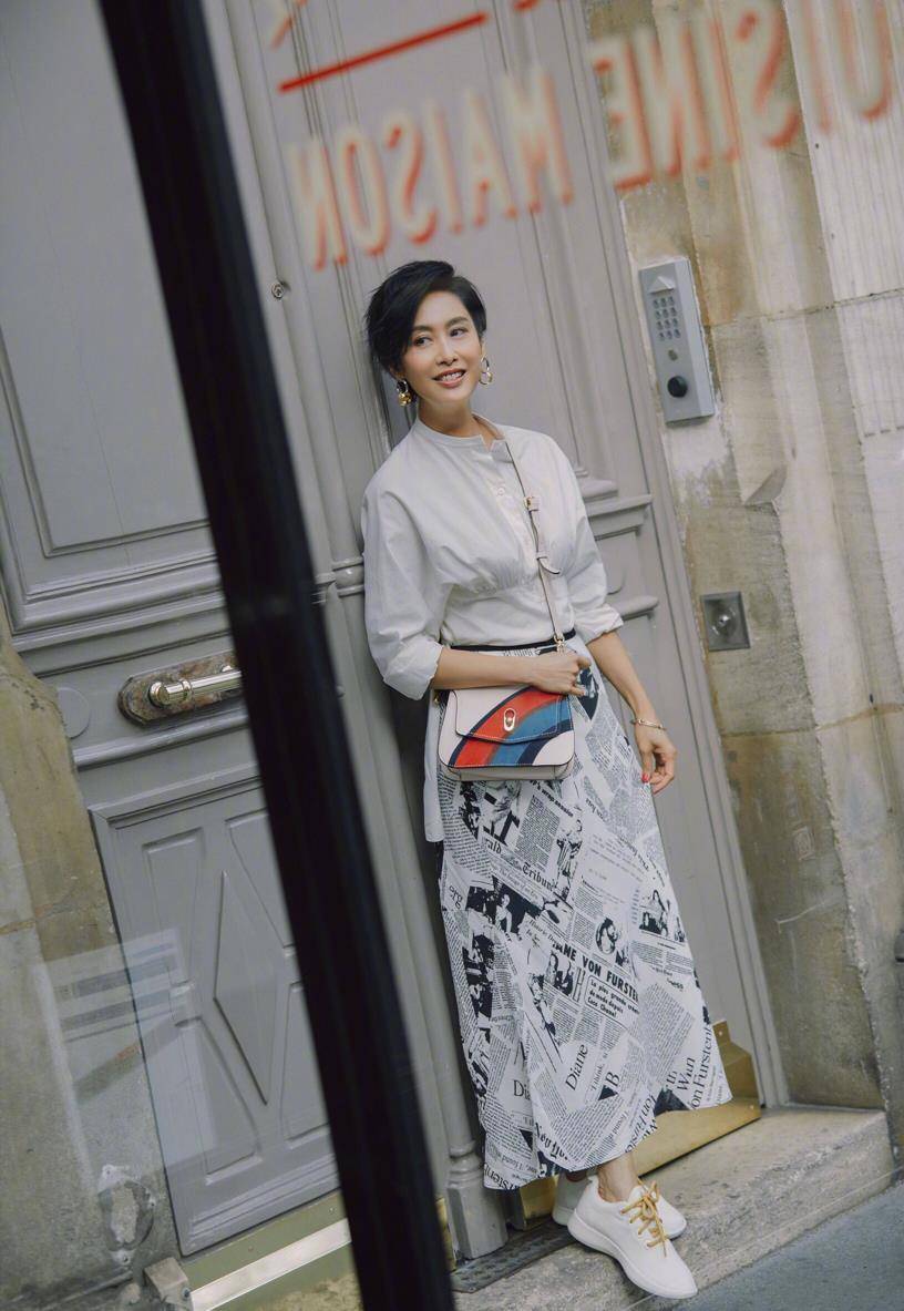 朱茵身穿粉色白色丝绸衬衣搭长半裙,黑白色"报纸"印花搭配,凸显文艺