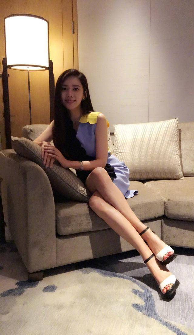 在沙发里的秋瓷炫穿了条紫色与白色平分天下的短裙,搭配同种色调凉鞋