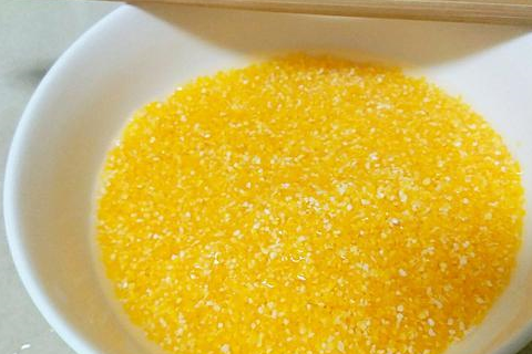 将打好的奶油南瓜糊倒入电饭煲内,再加入淘洗干净的玉米渣,放入适量