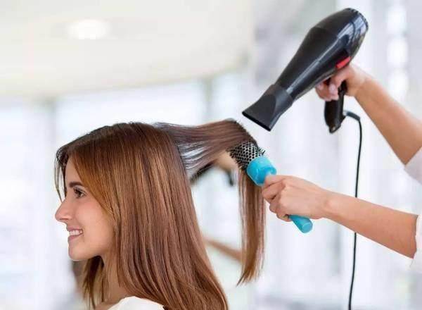 (2),使用卷梳挑起一缕头发,然后一手拿卷梳,一手拿吹风机向下旋转吹