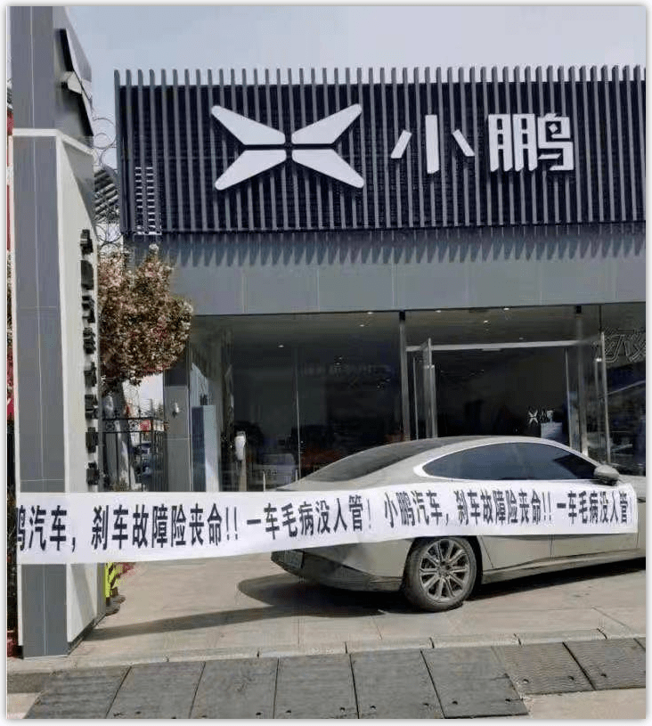 一位车主将一辆小鹏g7停在小鹏汽车门店前,拉起一张白底黑字的条幅,上