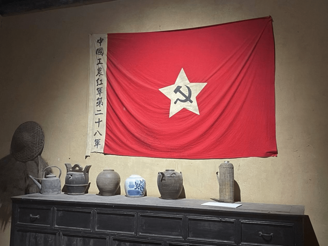 图为高敬亭住所中悬挂的中国工农红军第二十八军军旗图为讲解员为指导