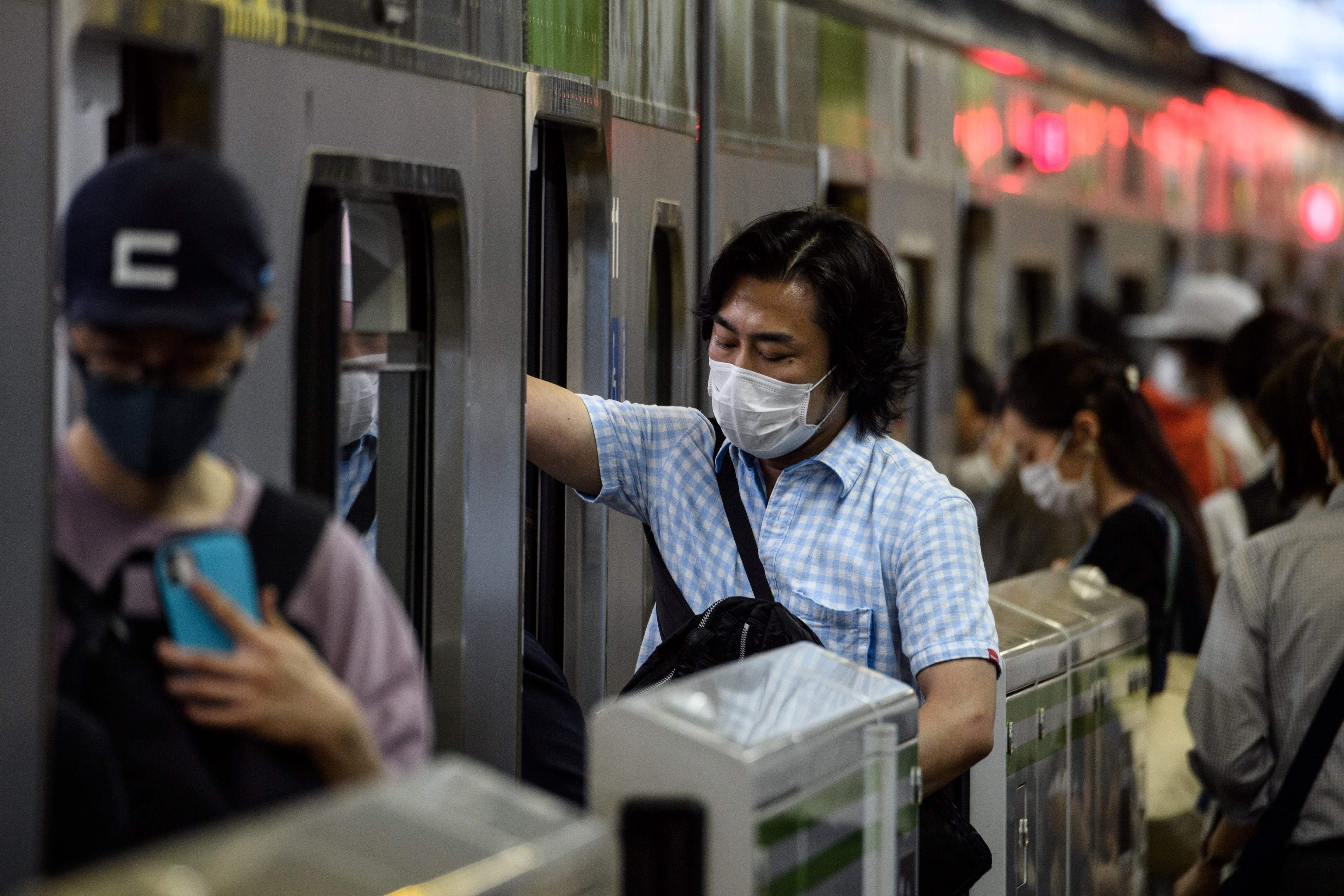 6月24日,在日本东京品川车站,人们戴口罩上车.