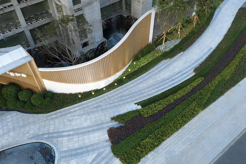 大门入口以流畅的弧形景墙结合层级的木制竖格栅打造出开阔恢弘而不失