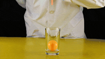 第二步,用吸管向下朝杯子吹气,乒乓球飘了起来