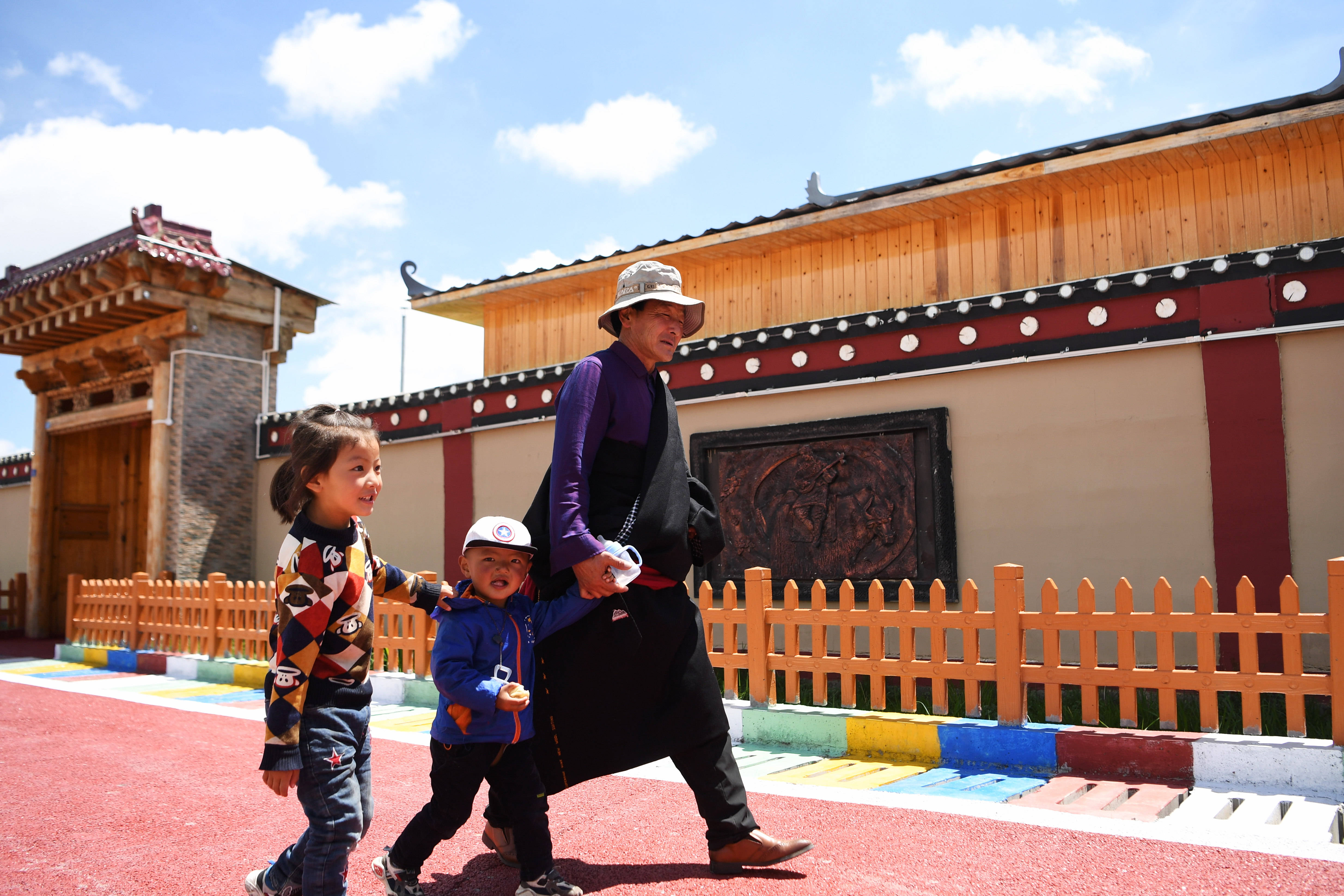 在甘南藏族自治州碌曲县尕海镇尕秀村,村民格日扎西(右)带着孩子从村