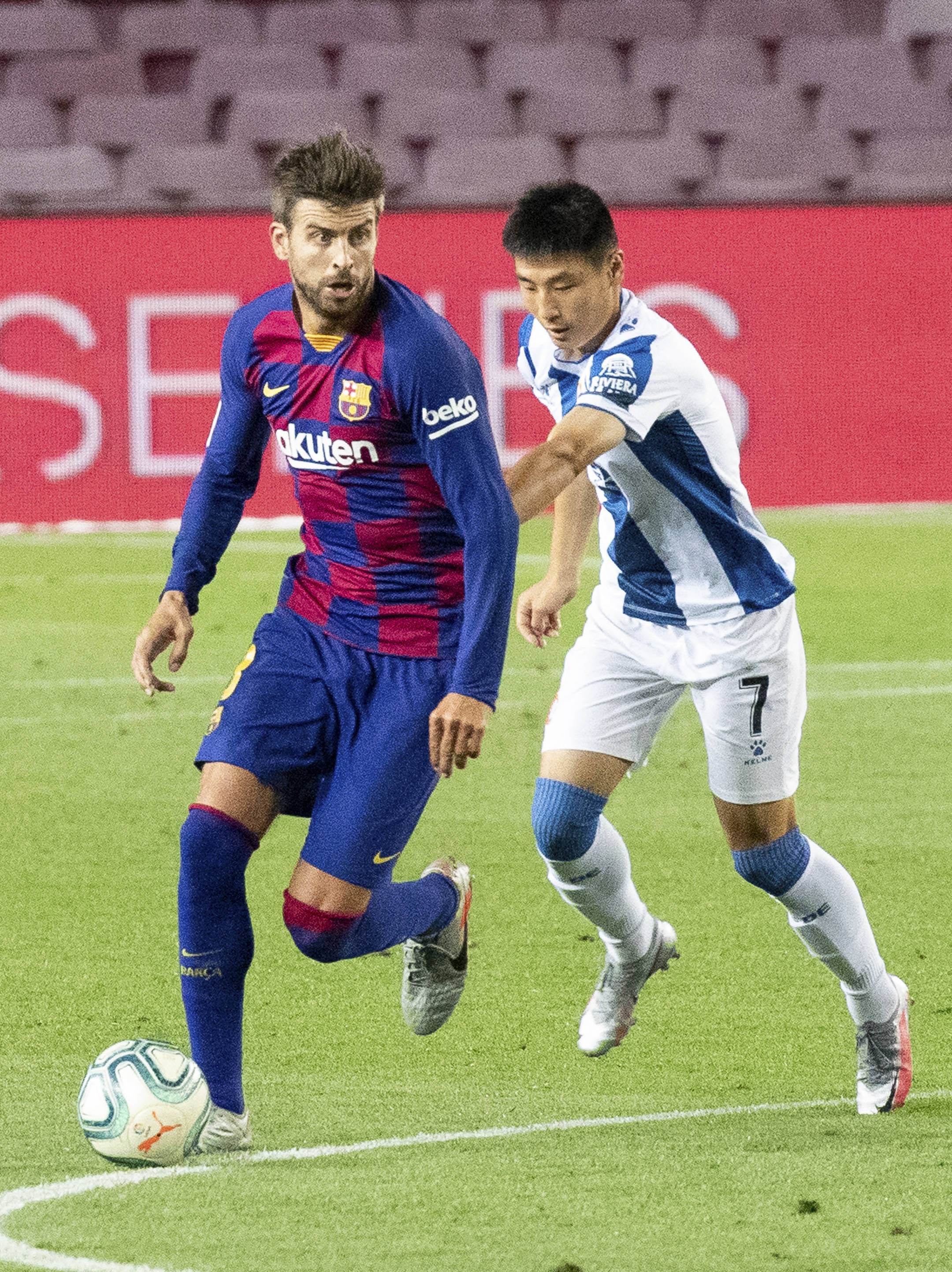 7月8日,西班牙人队球员武磊(右)在比赛中防守巴塞罗那队球员皮克.