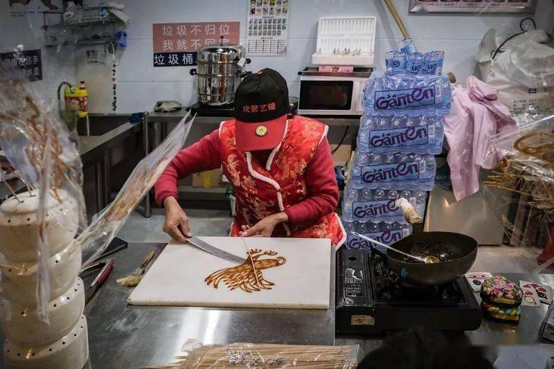 挑子的一头是熬糖的炉子,一头是绘糖画的石板和"转糖盘"