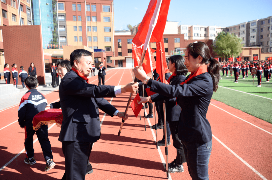 亚桥小学校党委领导为各中队授旗,并为中队辅导员颁发聘书.