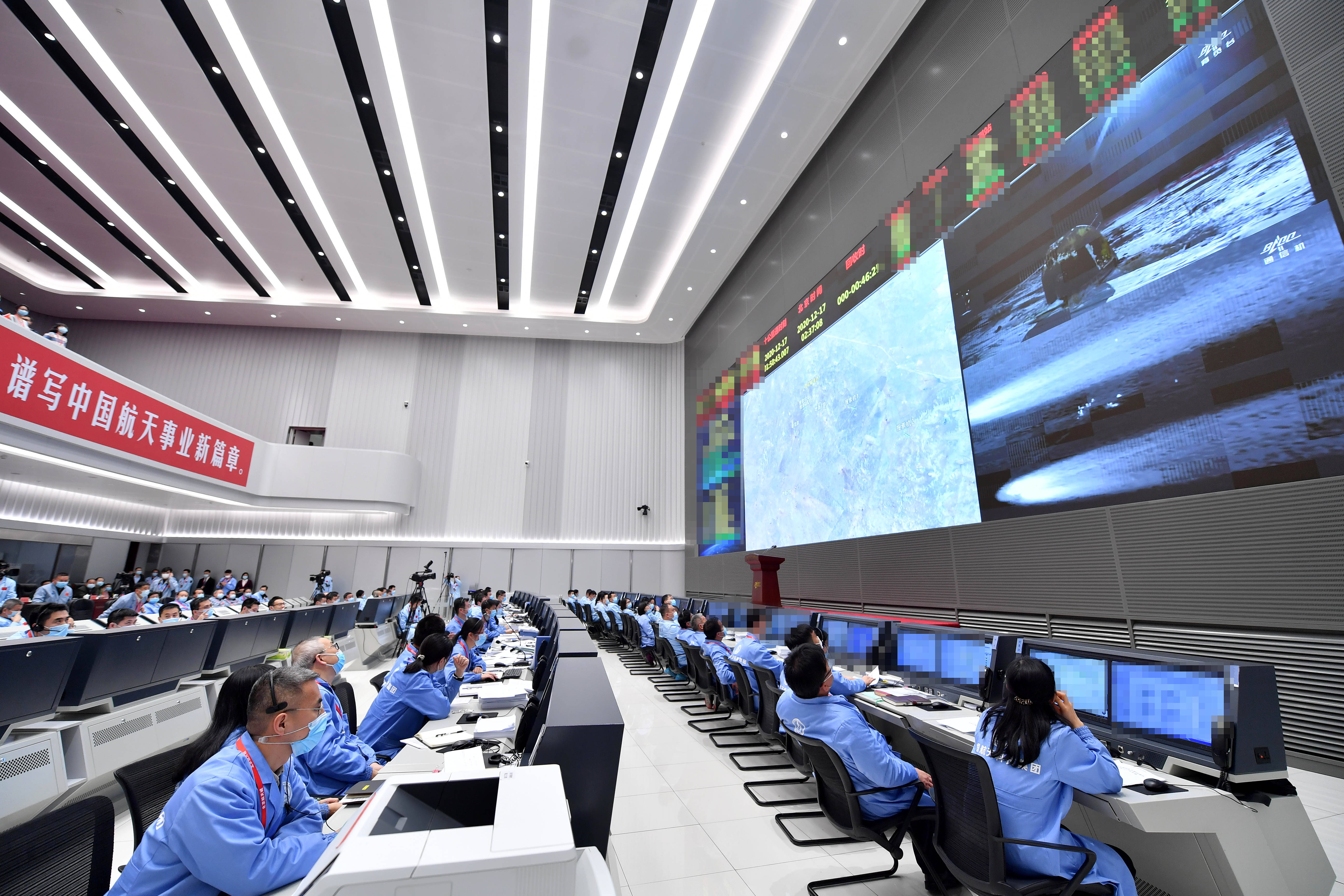 工作人员在北京航天飞行控制中心嫦娥五号任务飞控现场观看返回器携带