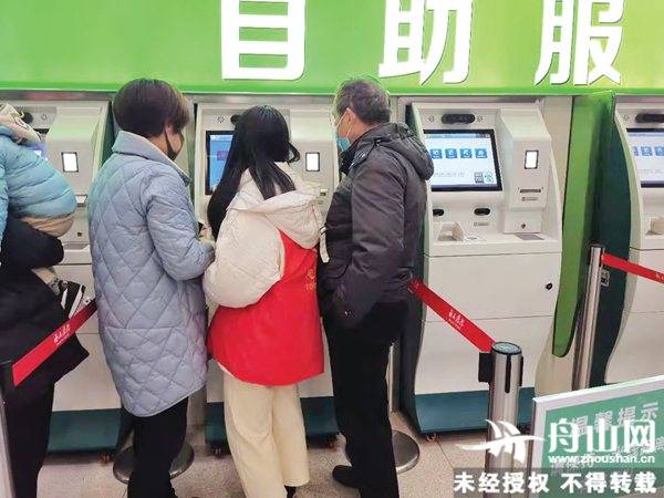 舟山医院自助服务机前,志愿者正在指导市民挂号.