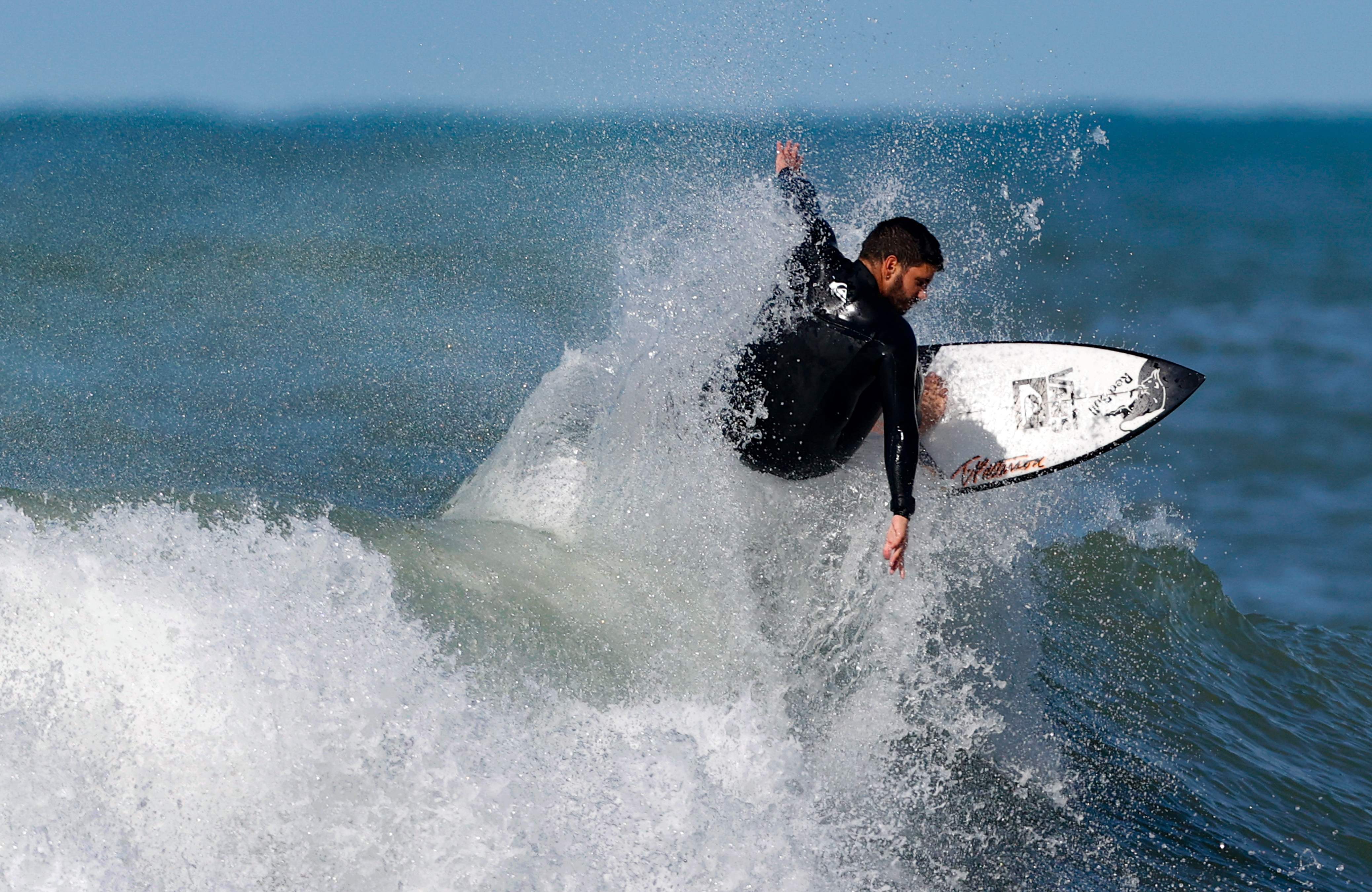 新华社照片,外代,2021年1月22日 1月21日,游客在以色列内坦亚玩冲浪.