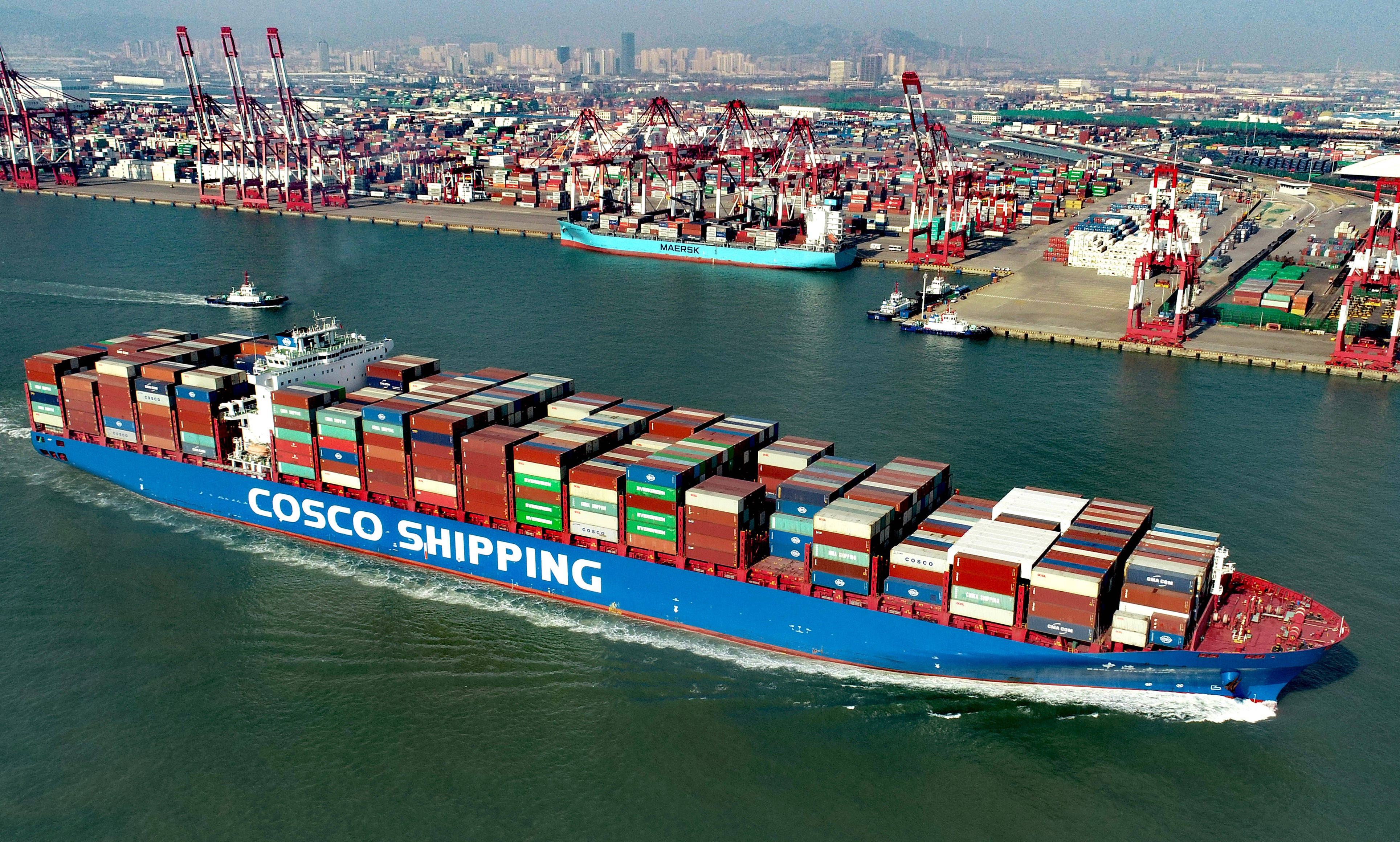 青岛港前湾集装箱码头,一艘满载集装箱的货轮驶出港口(无人机照片)