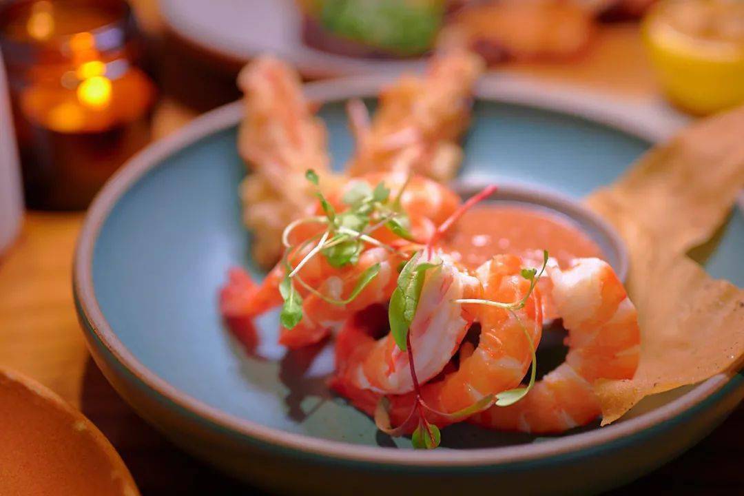 prawns are draped along the rim of a bowl of cocktail sauce