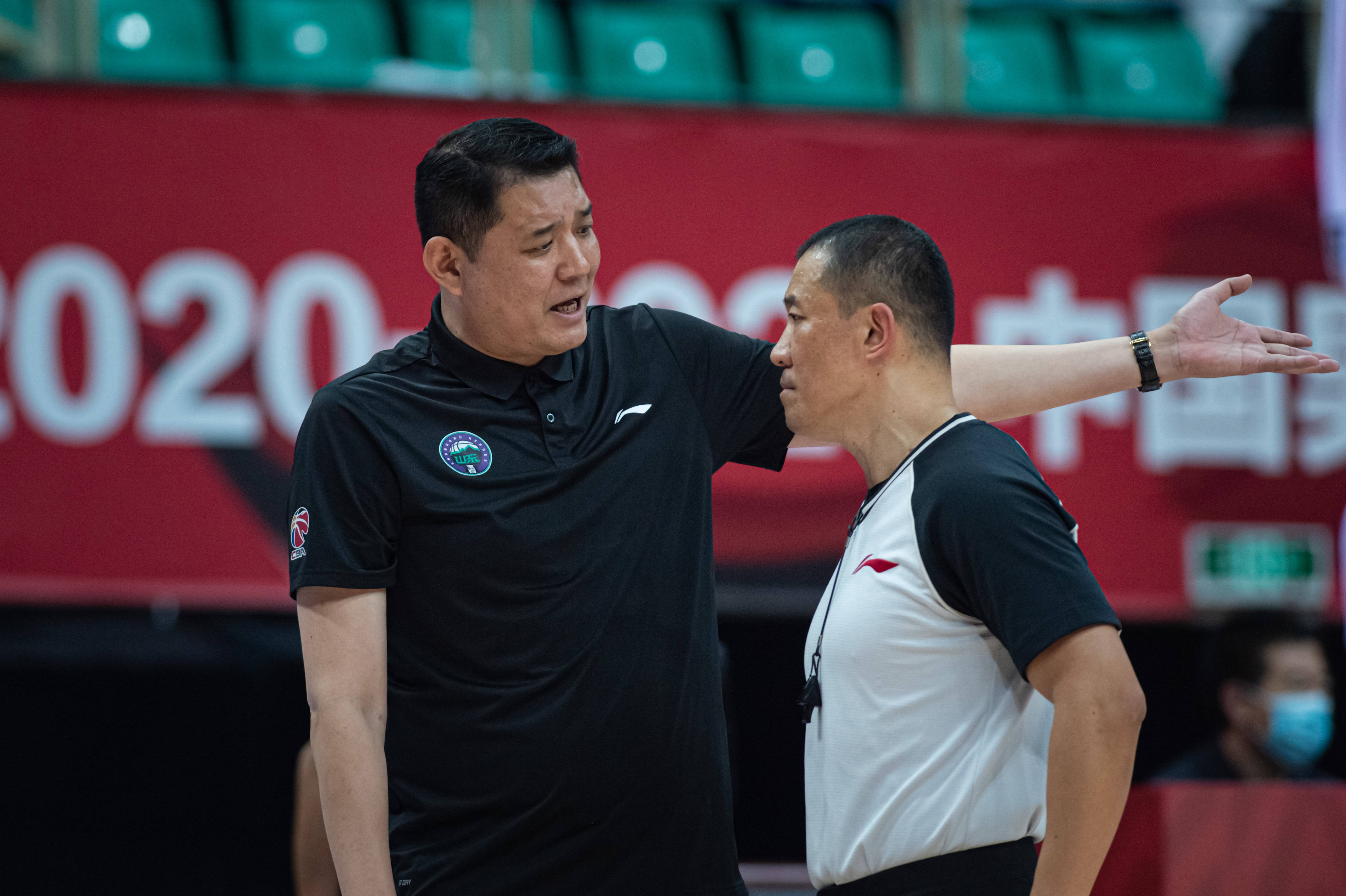 4月18日,山东西王队主教练巩晓彬(左)在比赛中与第一副裁判韩栩交流.