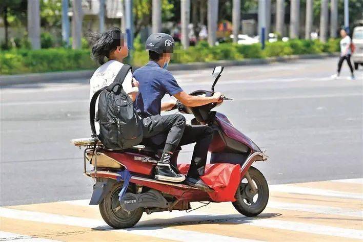 在燕罗街道塘下涌工业大道上,市民未正确佩戴头盔载人骑乘电动二轮车.